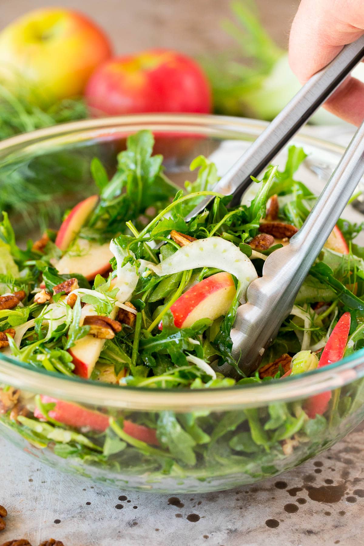 Tongs serving up a portion of fennel salad.