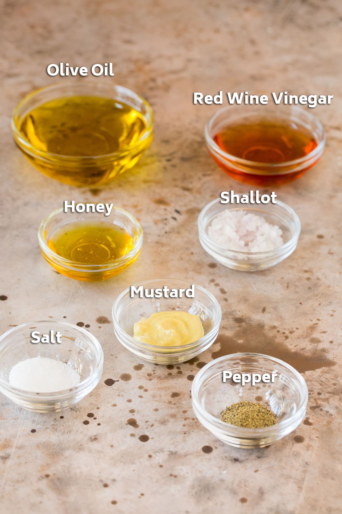 Bowls of salad dressing ingredients such as olive oil, vinegar and seasonings.