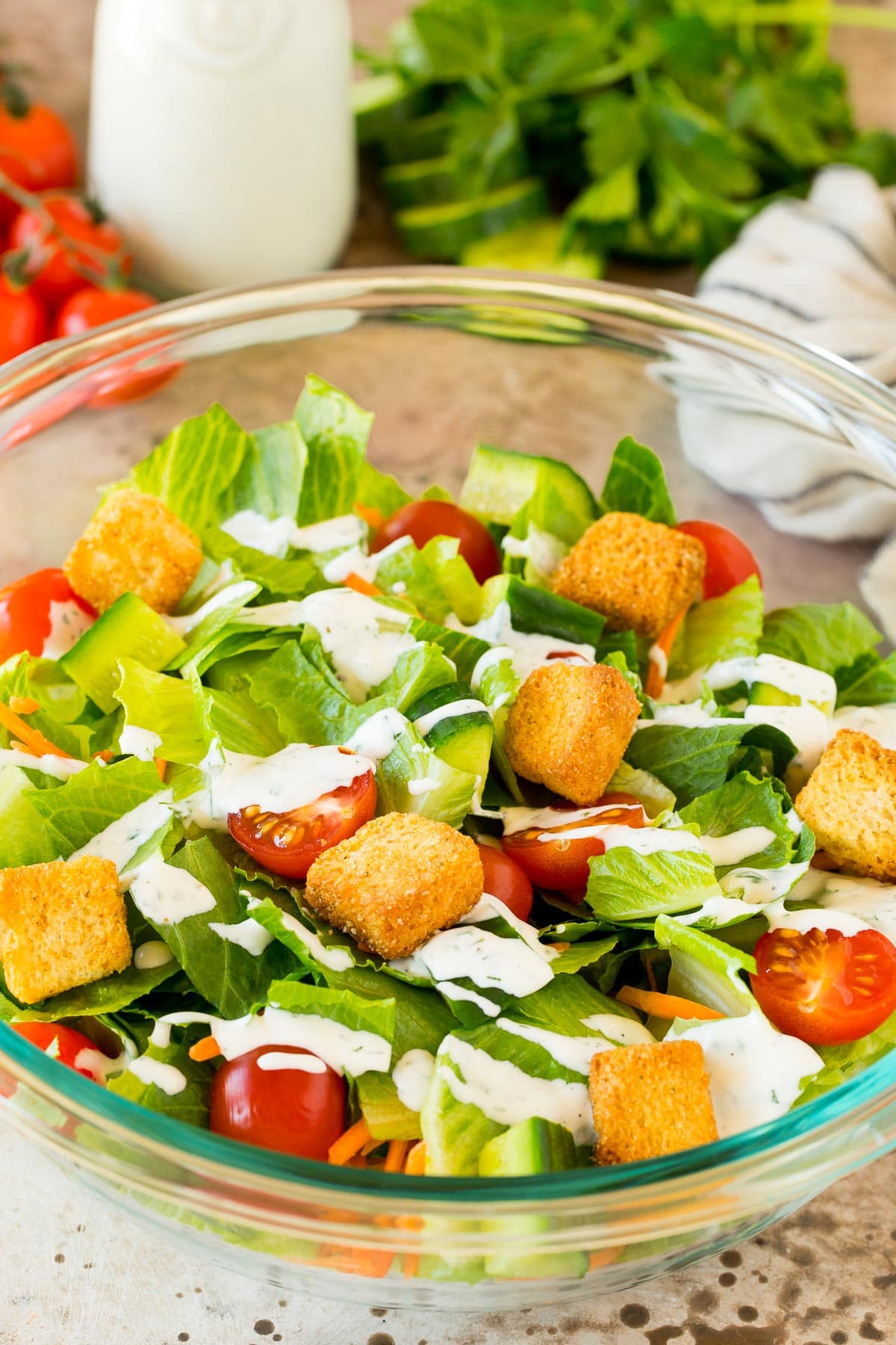 A green salad with homemade ranch dressing drizzled on top.