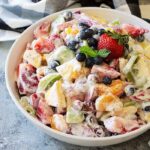 An image of fruit salad with strawberries, kiwi and other fruit in a creamy dressing.
