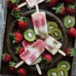 An image of several creamy strawberry kiwi popsicles.