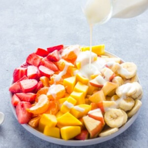 An image of fruit salad with yogurt sauce poured on top.