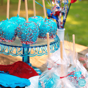 An image of a group of blue candy coated apples with red and white sprinkles.