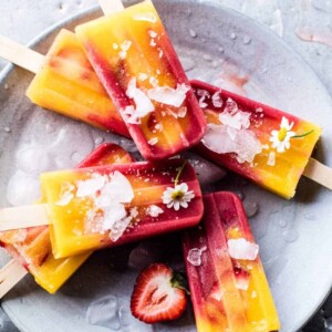 A picture of several strawberry mango popsicles in a bowl.