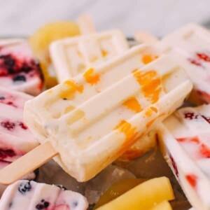 An image of several creamy popsicles with fruit in them.