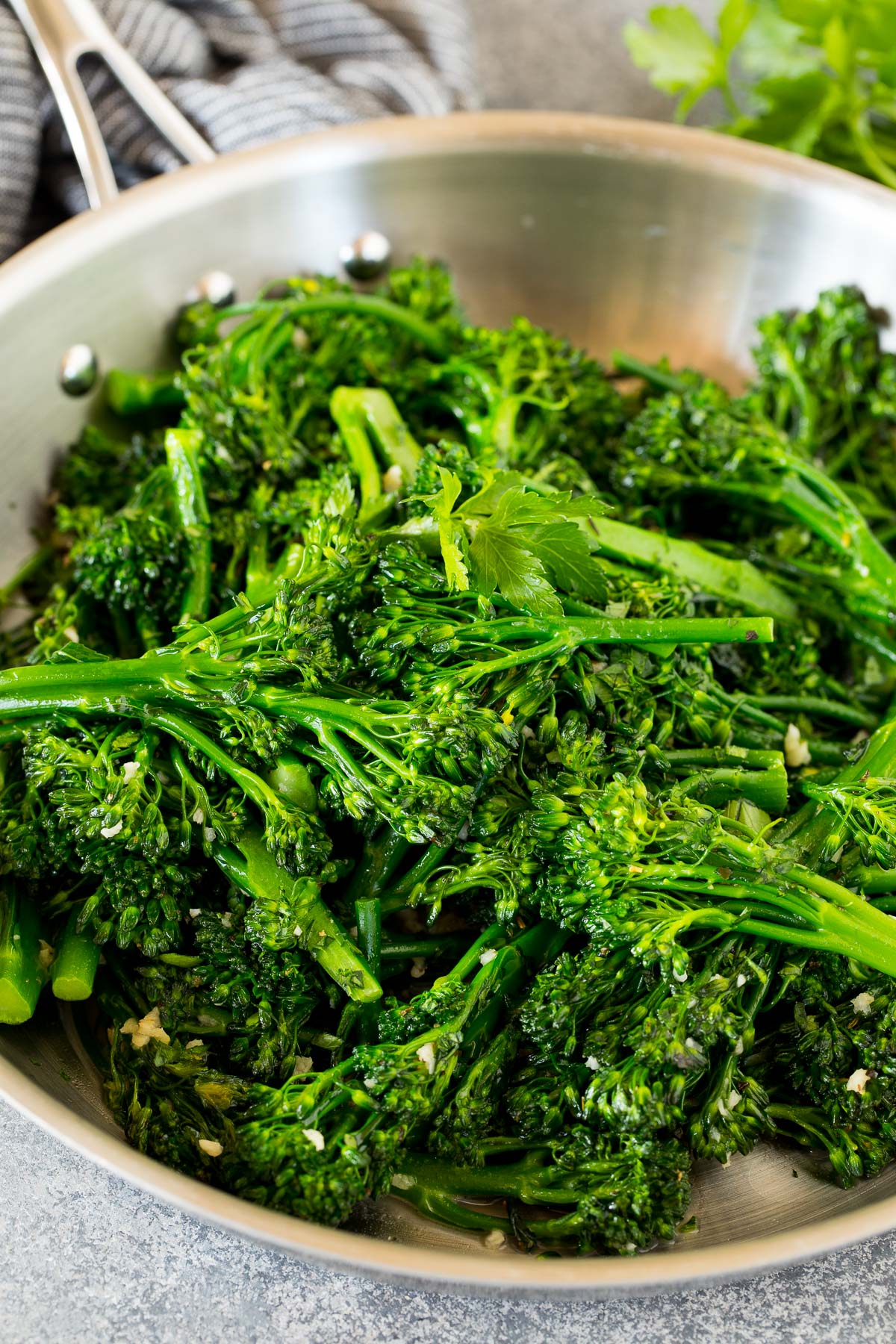Sauteed broccolini in a pan, topped with parsley.