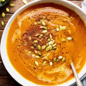 An image of a bowl of squash soup with seasoning on top.