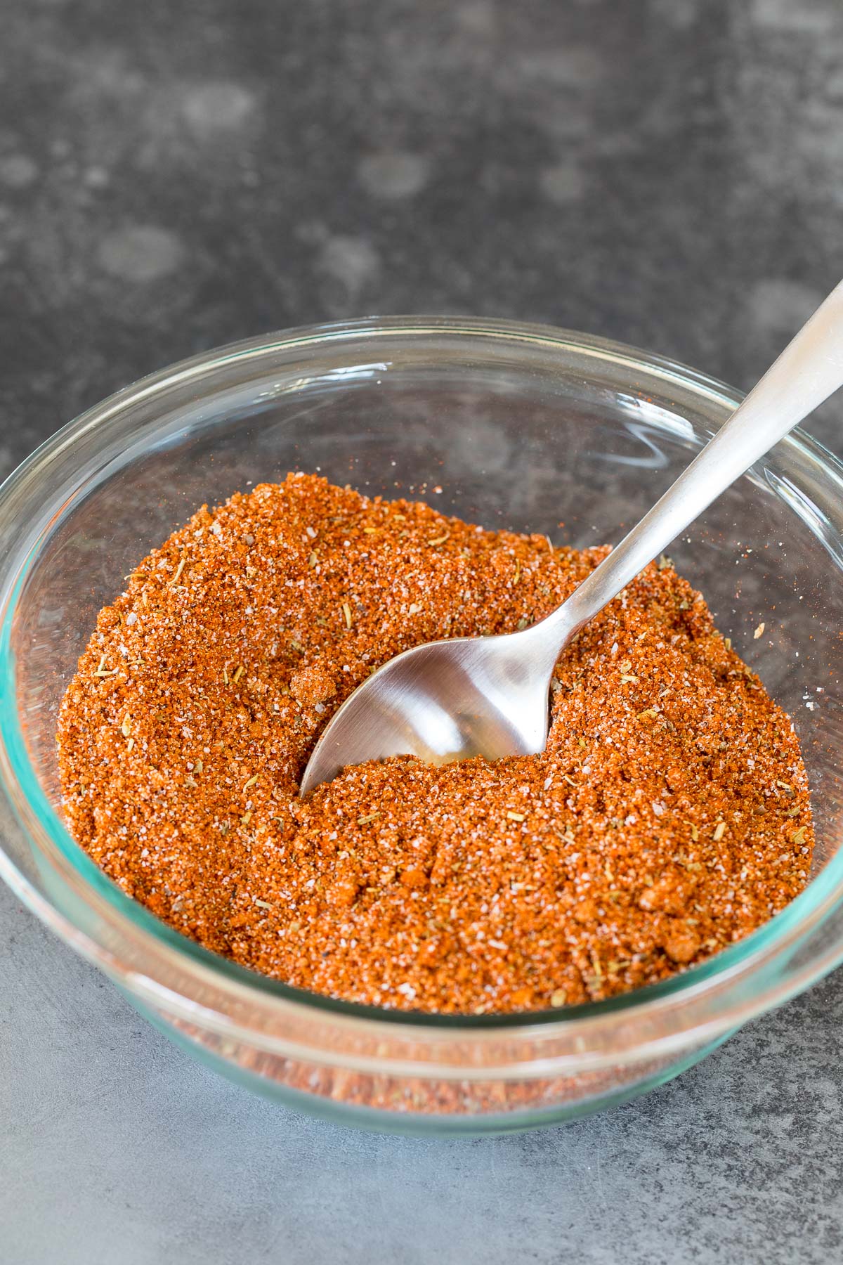 A bowl of seasoning mixed together with a spoon in it.