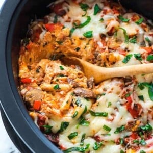 An image of crock pot pasta in crock pot with a wood spoon in the pasta..