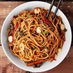 An image of slow cooker lo mein in a white bowl with black chopsticks.