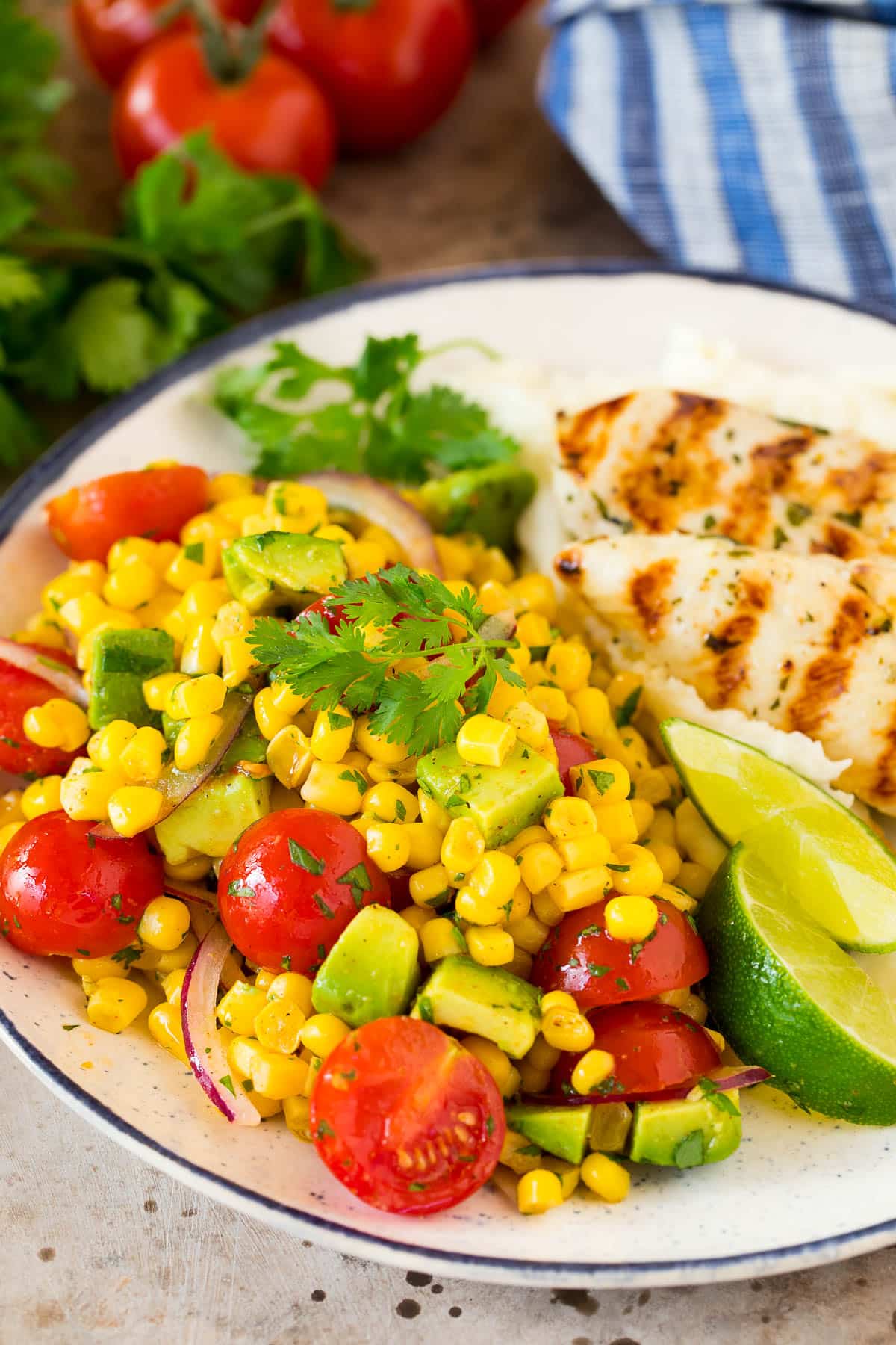Avocado corn salad on a plate with grilled chicken.