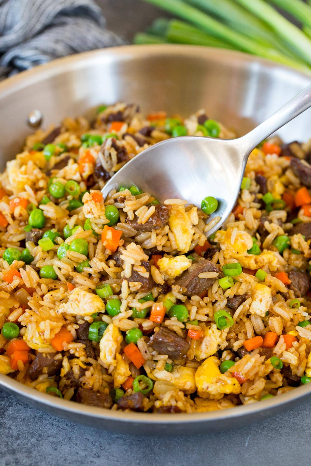 A pan of beef fried rice with a serving spoon in it.
