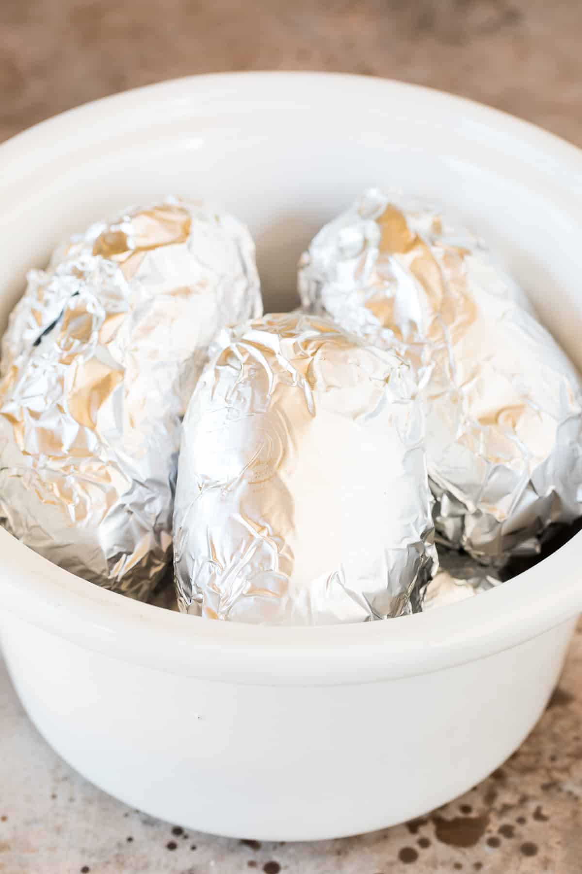 Potatoes wrapped in foil in a slow cooker.