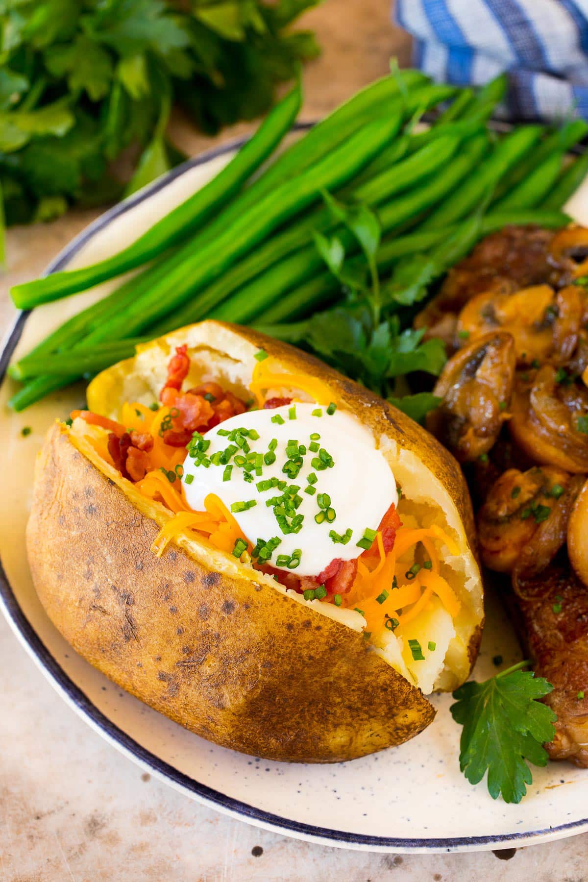 A crock pot baked potato served with steak and green beans.