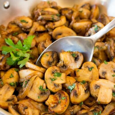 A spoon serving up a portion of sauteed mushrooms and onions.