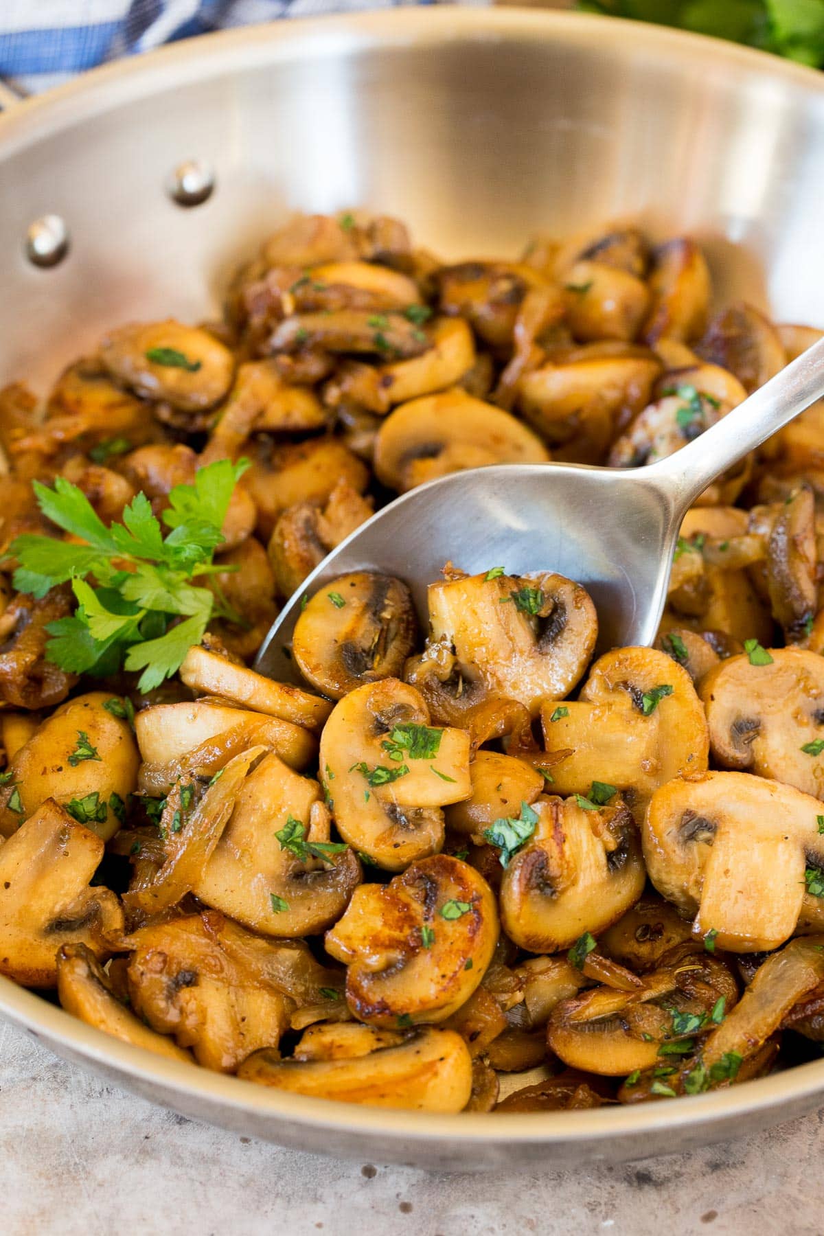 A spoon serving up a portion of sauteed mushrooms and onions.