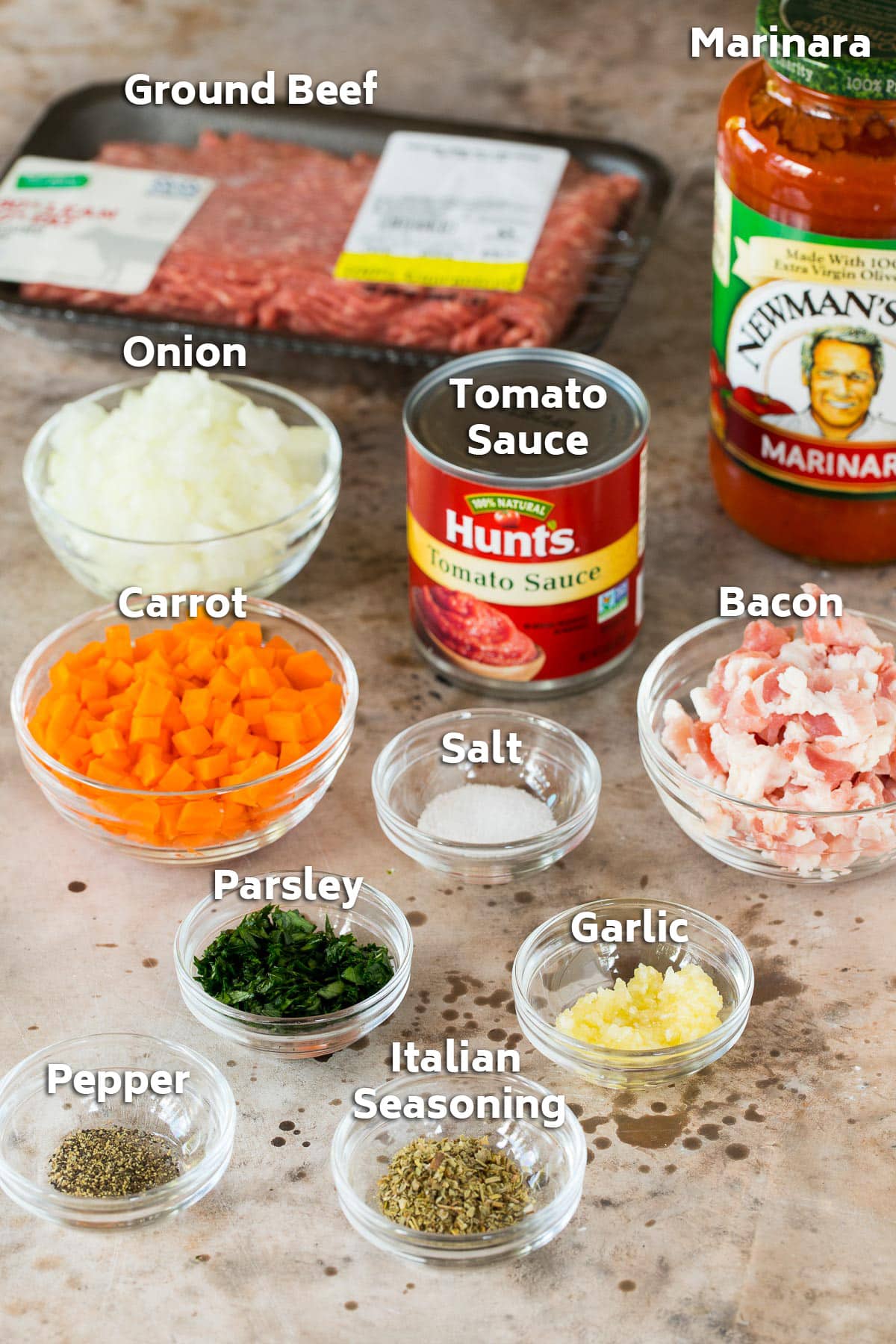 Ingredients including ground beef, bacon, vegetables and marinara sauce.