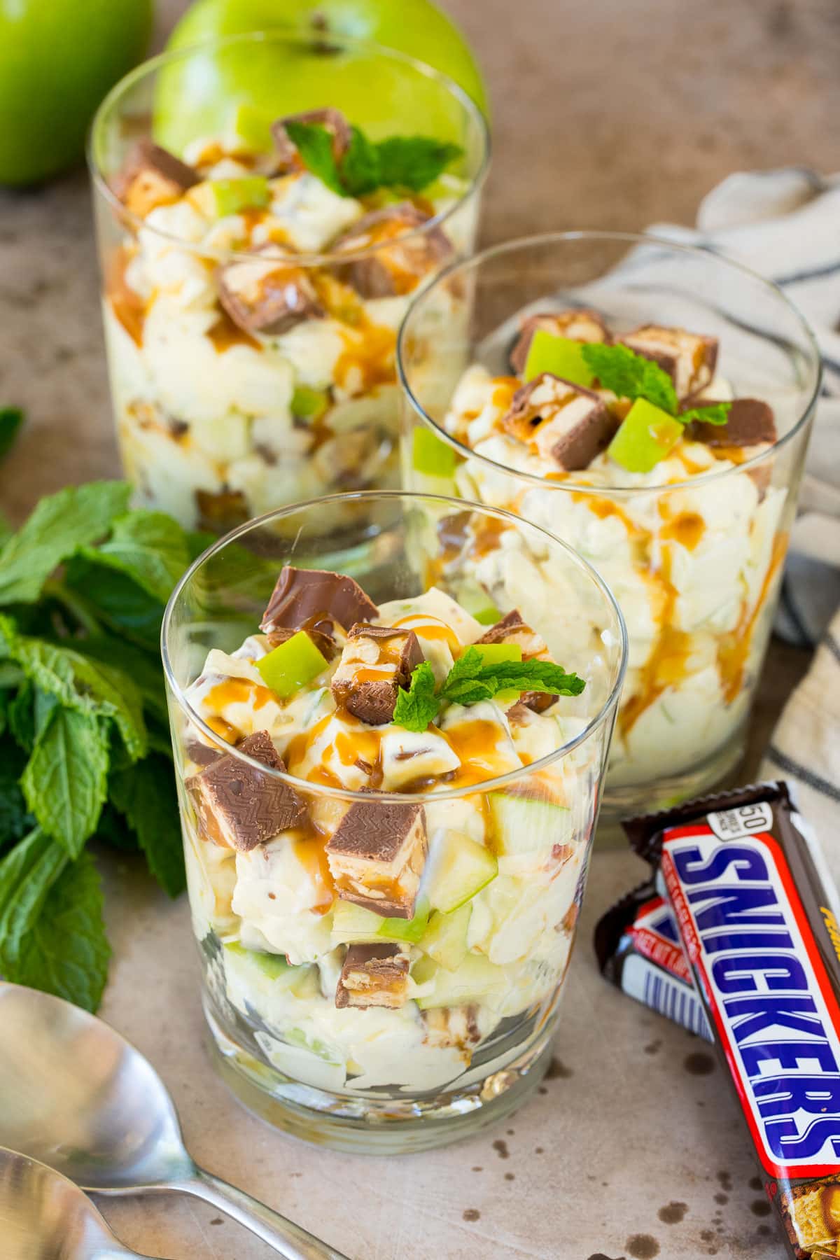 Individual servings of snicker apple salad garnished with caramel and mint.