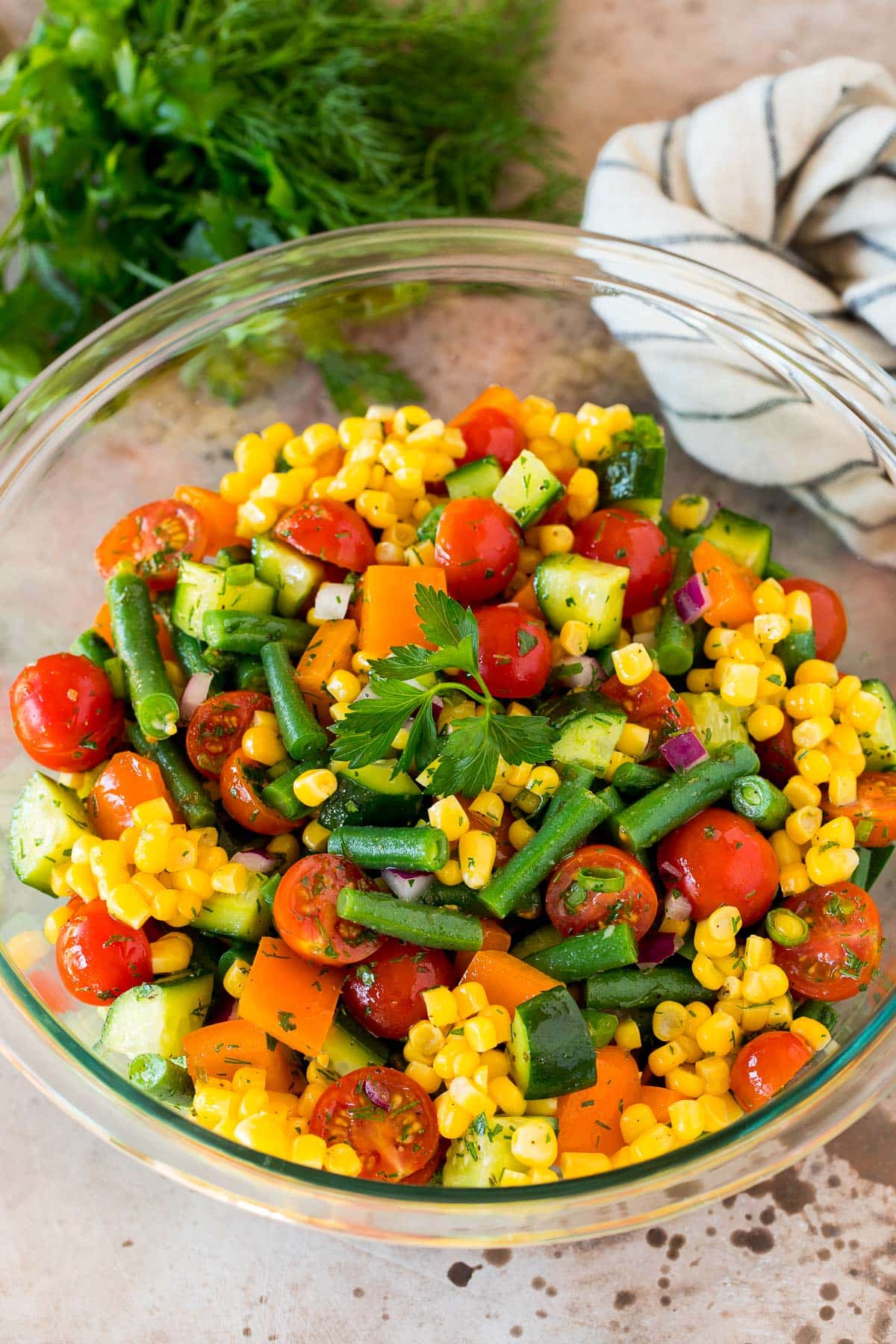 A bowl of chopped vegetable salad garnished with parsley.