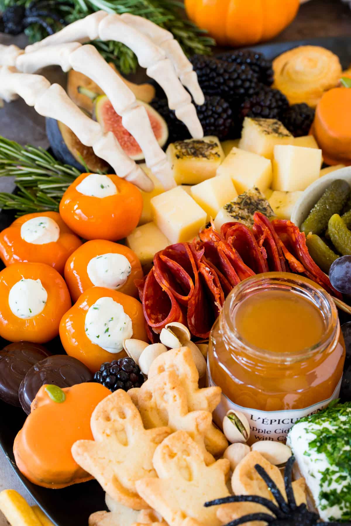 A close up shot of a Halloween charcuterie board with ghost cookies, meats and jam.