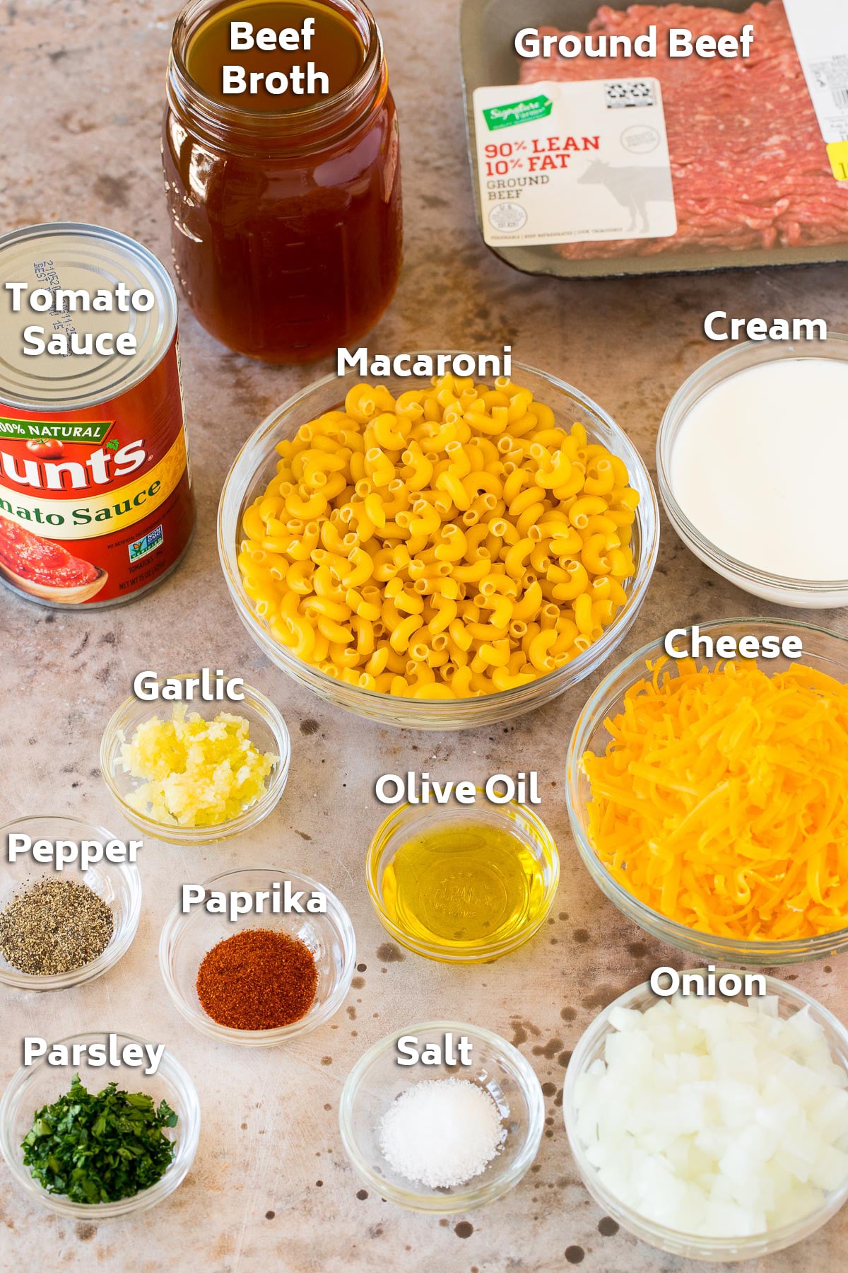 Bowls of ingredients including macaroni, cheese, seasonings and a package of ground beef.