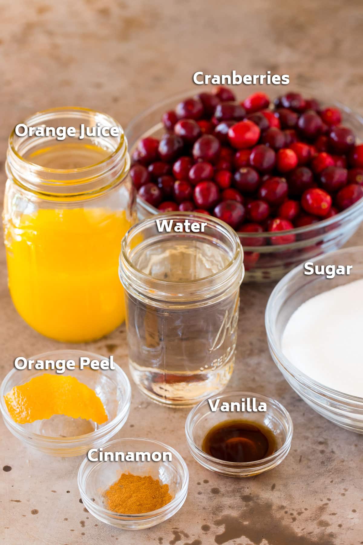 Bowls and jars of ingredients including cranberries, orange juice, and sugar.
