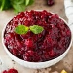 A bowl of slow cooker cranberry sauce garnished with mint.