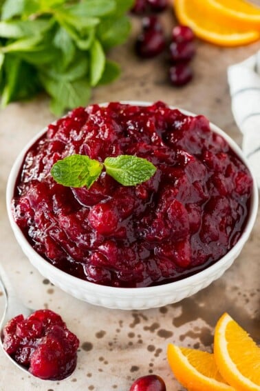 A bowl of slow cooker cranberry sauce garnished with mint.