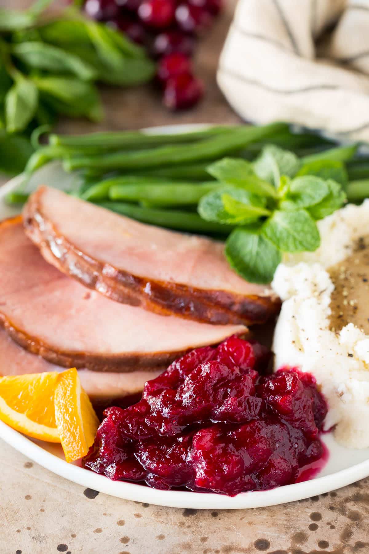 Slow cooker cranberry sauce on a plate with ham and mashed potatoes.