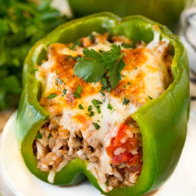 Stuffed green peppers on serving plates garnished with parsley.