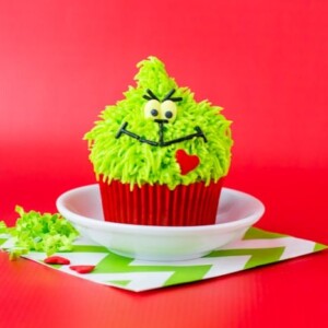 A picture of a grinch cupcake on a red background.