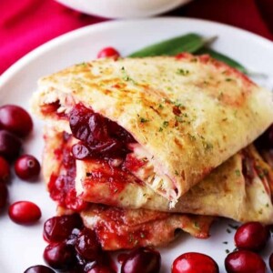 An image of turkey and cranberry quesadillas on a plate with cranberries.
