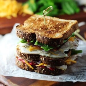 An image of two turkey club sandwiches on a cutting board.