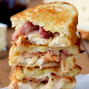 A picture of three turkey, bacon and brie sandwiches stacked.