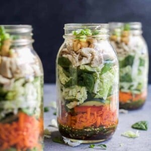A picture of chicken and salad in a mason jar.