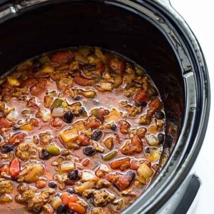 An image of a black slow cooker containing beefy black bean chili.