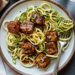 An image of a plate of sweet and spicy crispy tofu with zucchini noodles.
