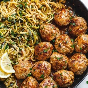 A picture of garlic butter meatballs next to lemon zucchini noodles.
