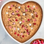 An image of a heart shaped large cookie with red and pink M&M candies.