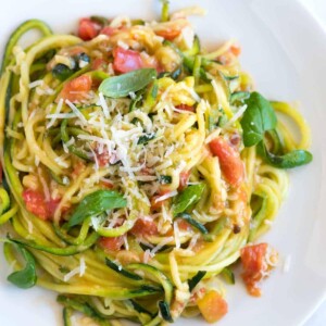 An image of zucchini noodles pasta with garlic, tomatoes and basil.