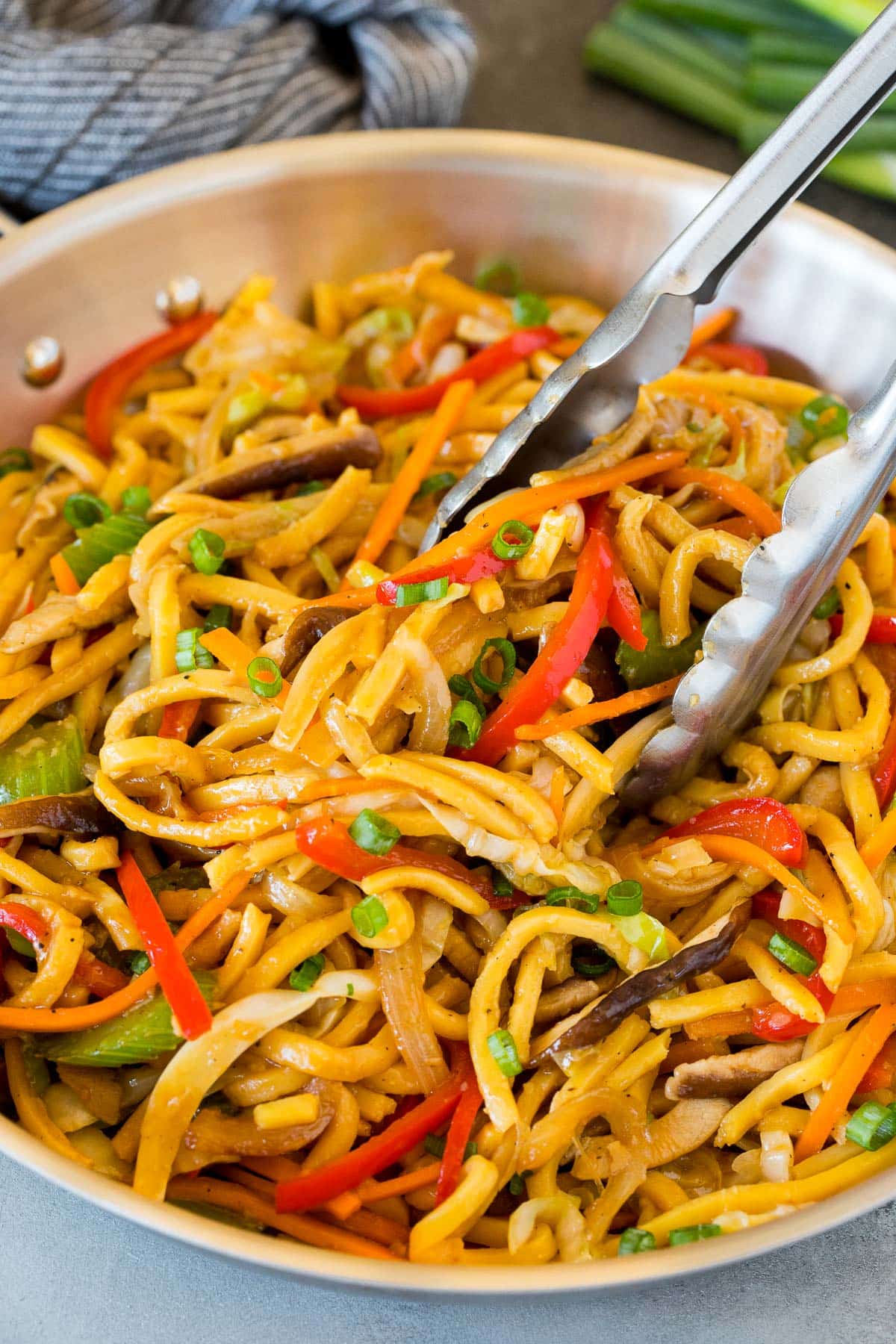 Tongs in a pan of vegetable lo mein.