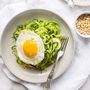 A picture of Zucchini Noodles with Pesto and Fried Eggs on a plate.