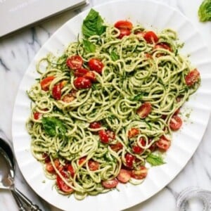 An image of a platter of zucchini pesto zoodles with tomatoes.