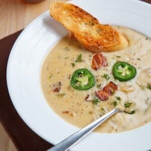 An image of a bowl of ale and cheddar soup with a toasted crust of bread.