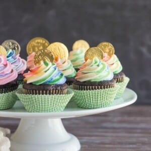 A picture of several pot of gold cupcakes on a platter.