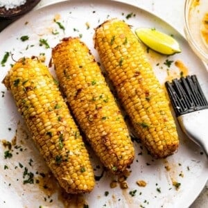 An image of three ears of air fryer corn on the cob on a plate.