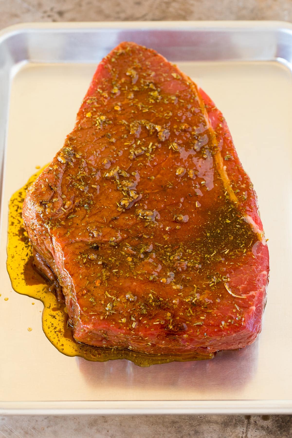 A piece of marinated beef roast on a sheet pan.
