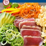 An image of an ahi tuna salad with carrots, cucumbers, lettuce and avocado in a bowl.