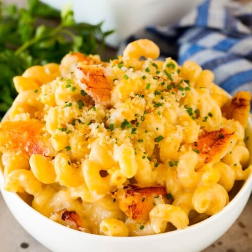 A bowl of crab mac and cheese topped with herbs.