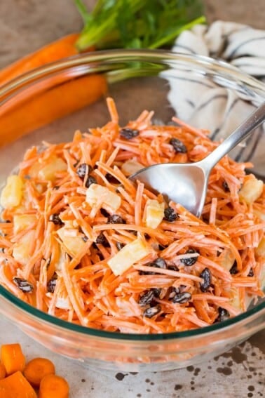 A serving bowl of carrot salad with a spoon in it.